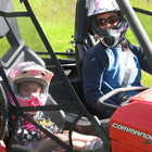 Photo of a women driving a UTV with her small daughter in the seat next to her. 