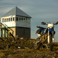 A dirt bike parked by a fire lookout tower. 