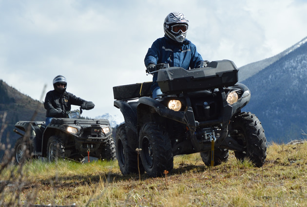 Two ATVers riding along the ridge of a mountain. 