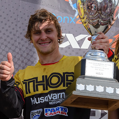 Tyler Medaglia holds his trophy up on the podium. 