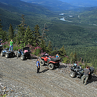 A group of ATVs riding up a logging road. 