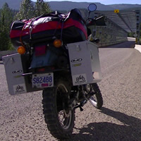 A man in yellow riding gear standing behind a dual-sport bike. 