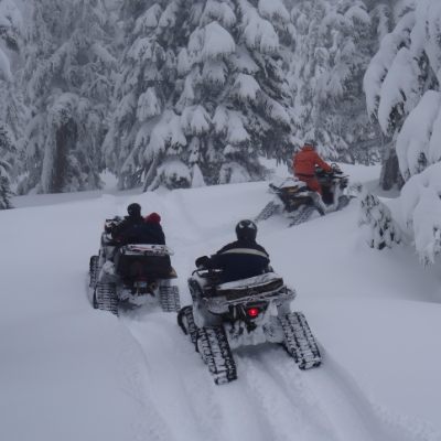 Three ATVs with tracks ride through the snow