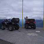 Two quads parked on a platform overlooking a mountain range.