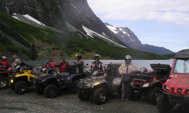 A group of ATVer parked in front of an alpine lake. 