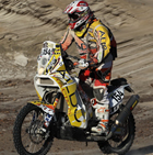 A man riding across the sand on a bike. 