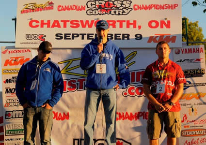 Photo of three men standing on a podium making speeches.