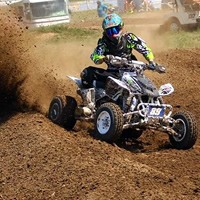 A roost of dirt as an ATV racer comes around the corner. 