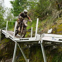 A man riding a dirt bike along a boardwalk. 