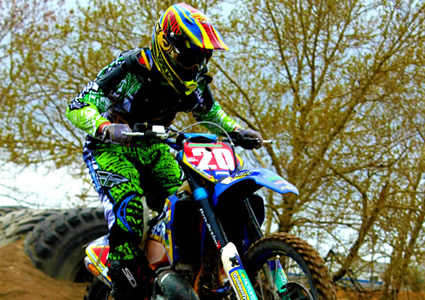 Photo of a guy riding over tires on a dirt bike. 