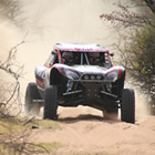 Photo of an off-road vehicle racing across sand. 