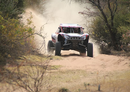 Photo of an off-road vehicle racing across sand. 