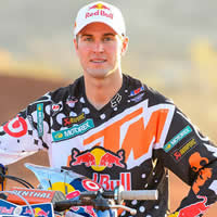 Ryan Dungey standing beside his KTM wearing a white Red Bull cap. 