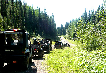 Photo of a line of ATVers driving down a path