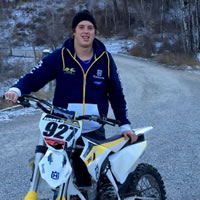 Two brothers standing beside Husqvarna dirt bikes. 