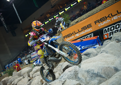 A woman riding a blue bike over rock obstacles. 