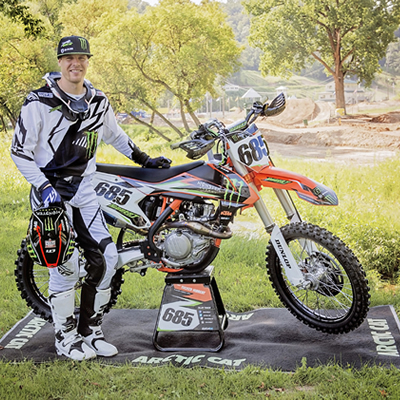 Tucker Hibbert standing beside his motocross bike. 