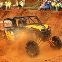 A side by side riding through a mud pit. 