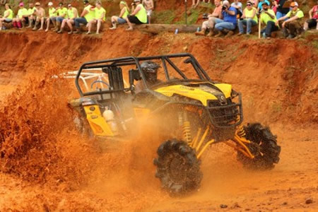 A side by side riding through a mud pit. 