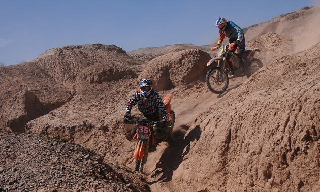 Two dirt bike riders going downhill at the ISDE. 