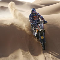 Kurt Caselli racing over a sand dune on his KTM. 