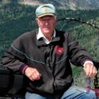 Photo of a man sitting on a red quad with the mountains in the background. 