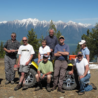 A group of people sitting together around a quad at the top of a mountain. 