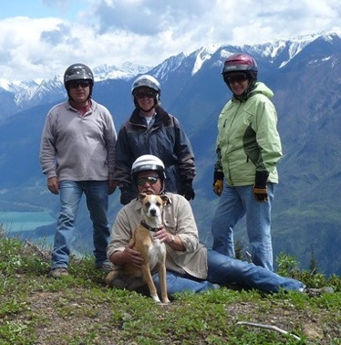 Phil and Delle Megyesi,  Tom and Beryl Maxwell and Phil's dog cooper are posing on a hill with snowcovered mountains in the background. 