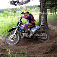 A woman coming around a corner on a dirt bike. 