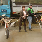 Photo of a man and a woman spraying off two dirt bikes. 