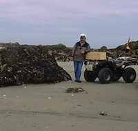 Phil Megyesi and his fellow riding partner standing by their quads on the beach.