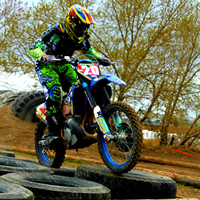 A dirt bike rider going over an obstacle of tires. 