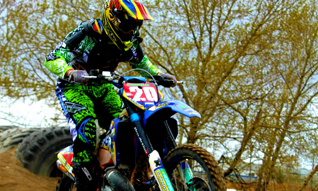 A dirt bike rider going over an obstacle of tires. 