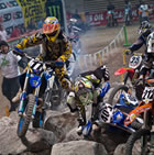 A guy navigating a man-made boulder obstacle on his dirt bike. 