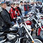 Women in a line standing beside their motorcycles