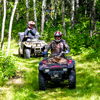 Two ATVer riding down grassy trail in Saskatchewan. 