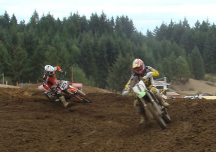 Photo of two riders railing a burm on a motocross track. 