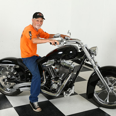 Jerry Wheelz sitting on a black Harley Davidson in the shop. 